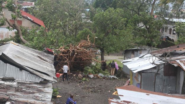 People stand by damaged houses and fallen trees in Comoros
